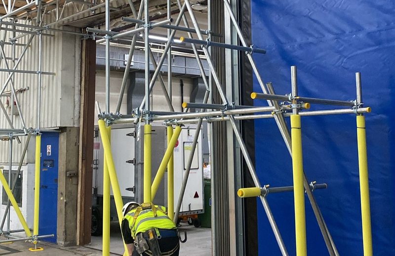 Arctic Scaffolding operative fixing a tower beside a hangar door