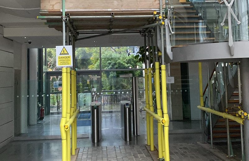 Arctic Group branded scaffold with protected walkway through an office atrium