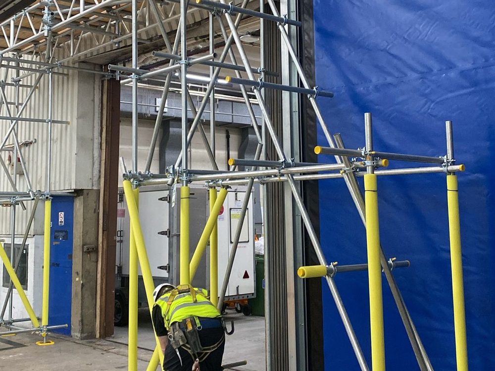 Arctic Scaffolding operative fixing a tower beside a hangar door