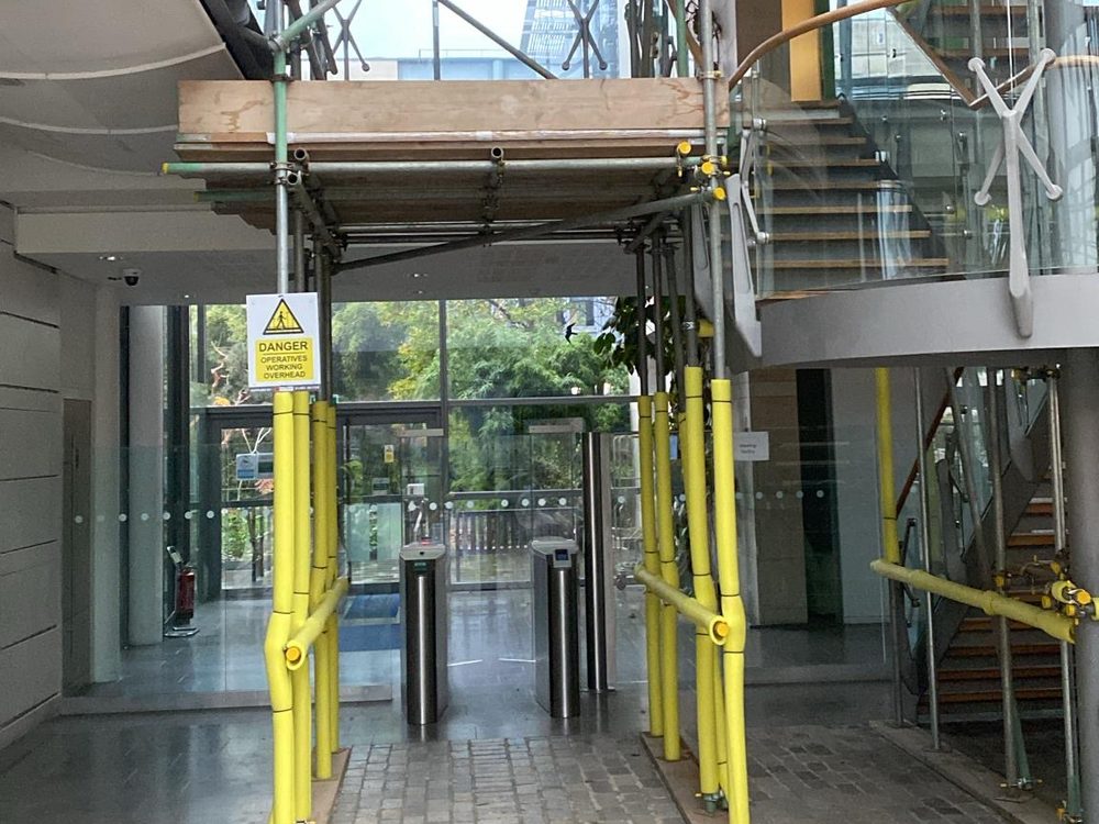 Arctic Group branded scaffold with protected walkway through an office atrium