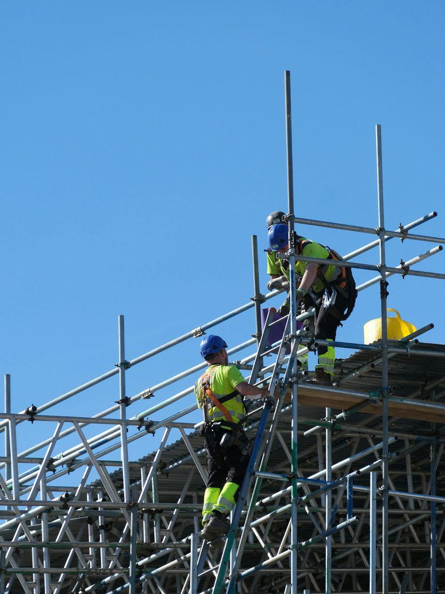 Arctic Scaffolding operatives in harnesses working on a scaffold against a blue sky